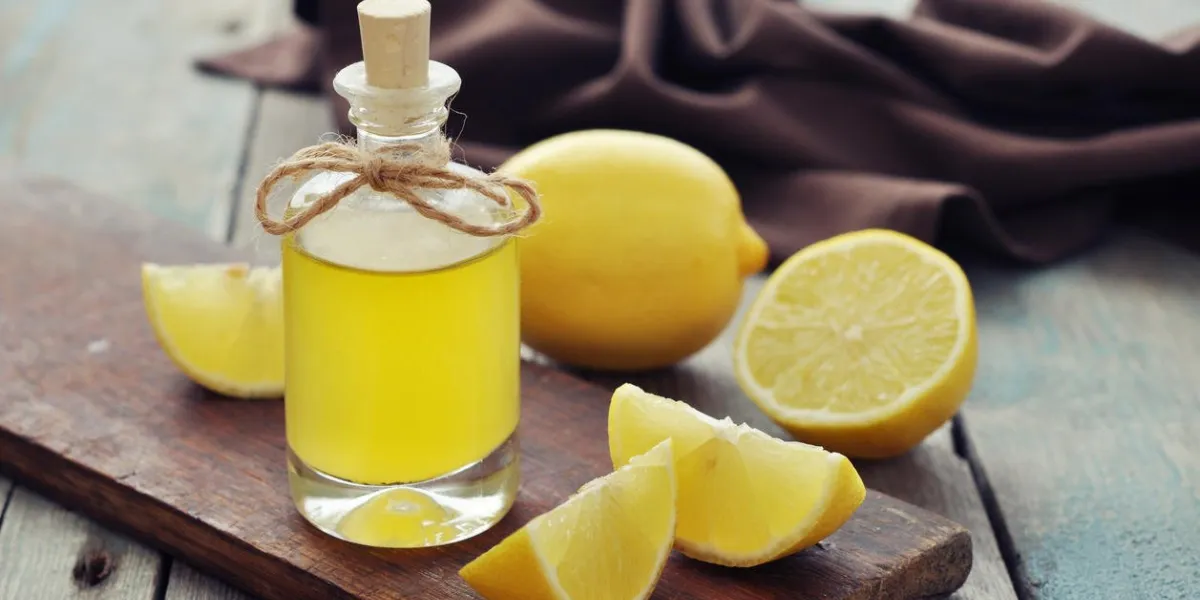 huile de citron dans une bouteille en verre avec du citron frais sur fond en bois