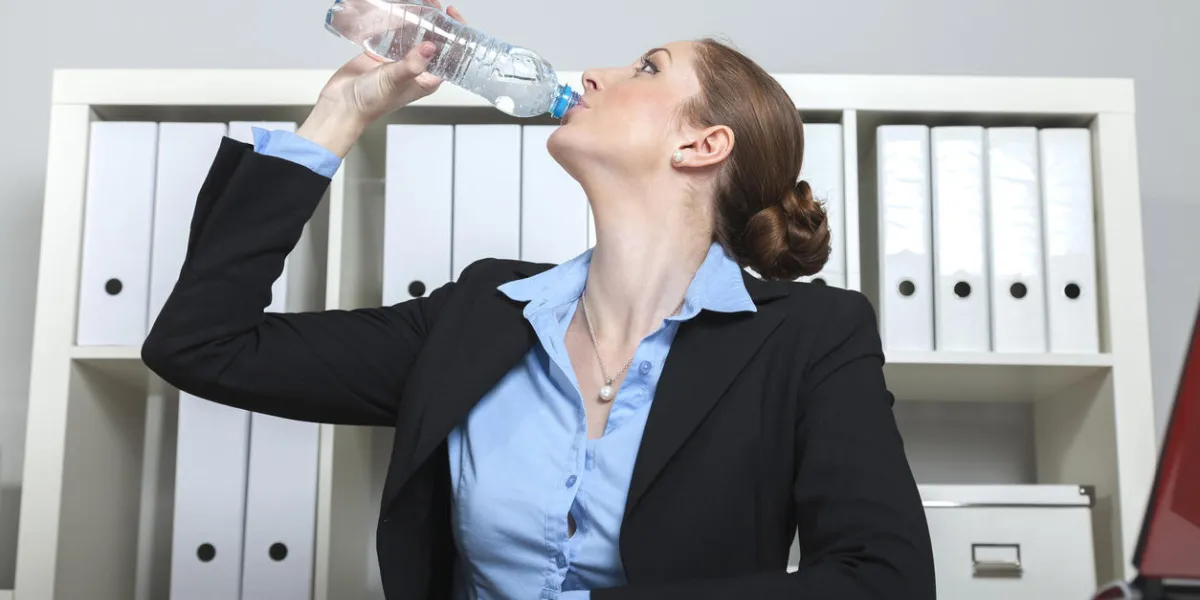 femme d'affaires boit de l'eau à partir d'une bouteille de polyéthylène