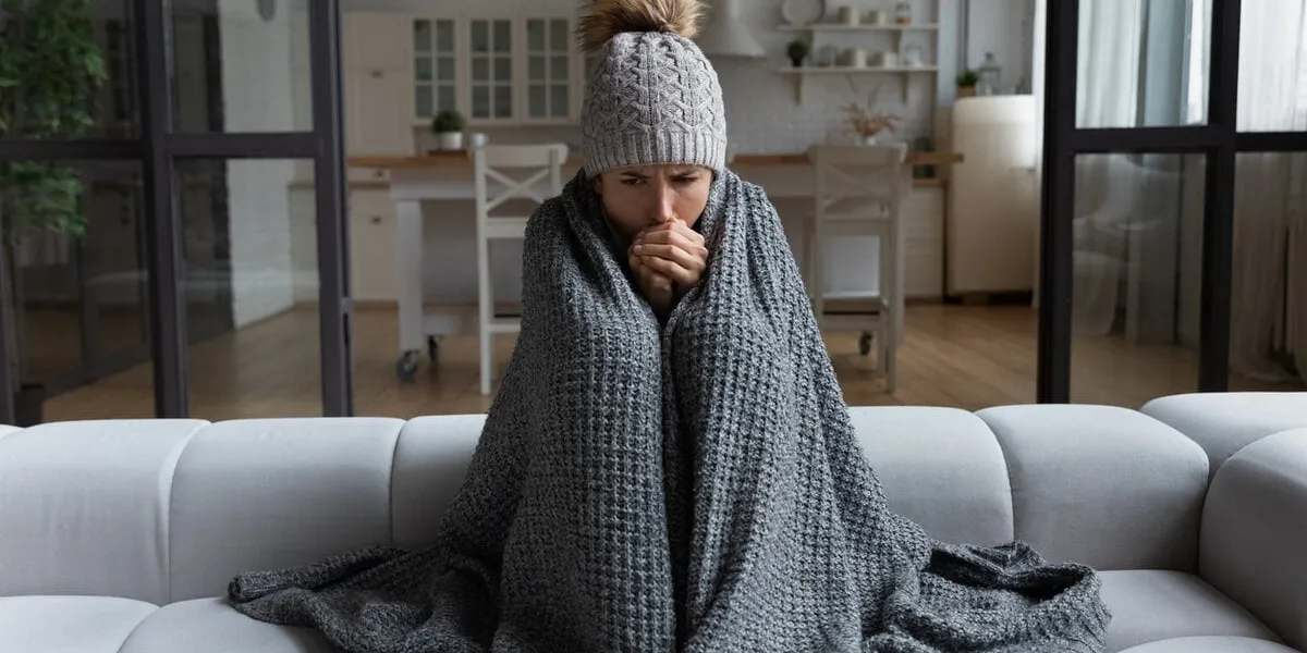 frozen sad latina female sit on couch at freezing cooled studio flat in warm cap and blanket shiver tremble with cold unhappy young lady spend time at home feel bad suffer of heating system problems