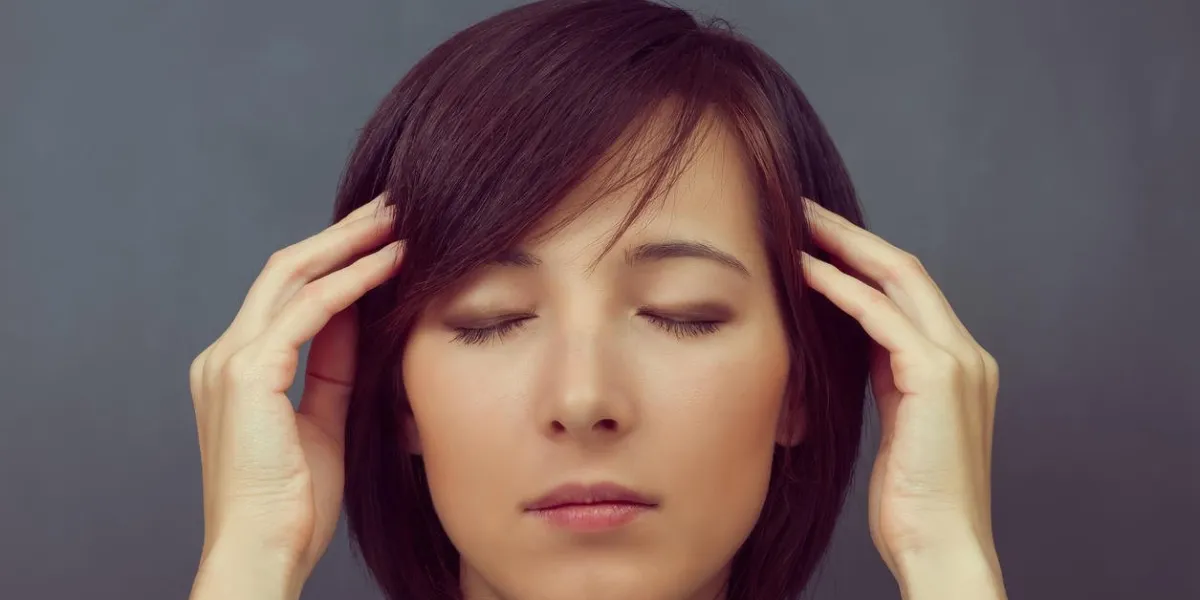 jeune femme touche sa tête sur un fond de tableau noir, notion de concentration