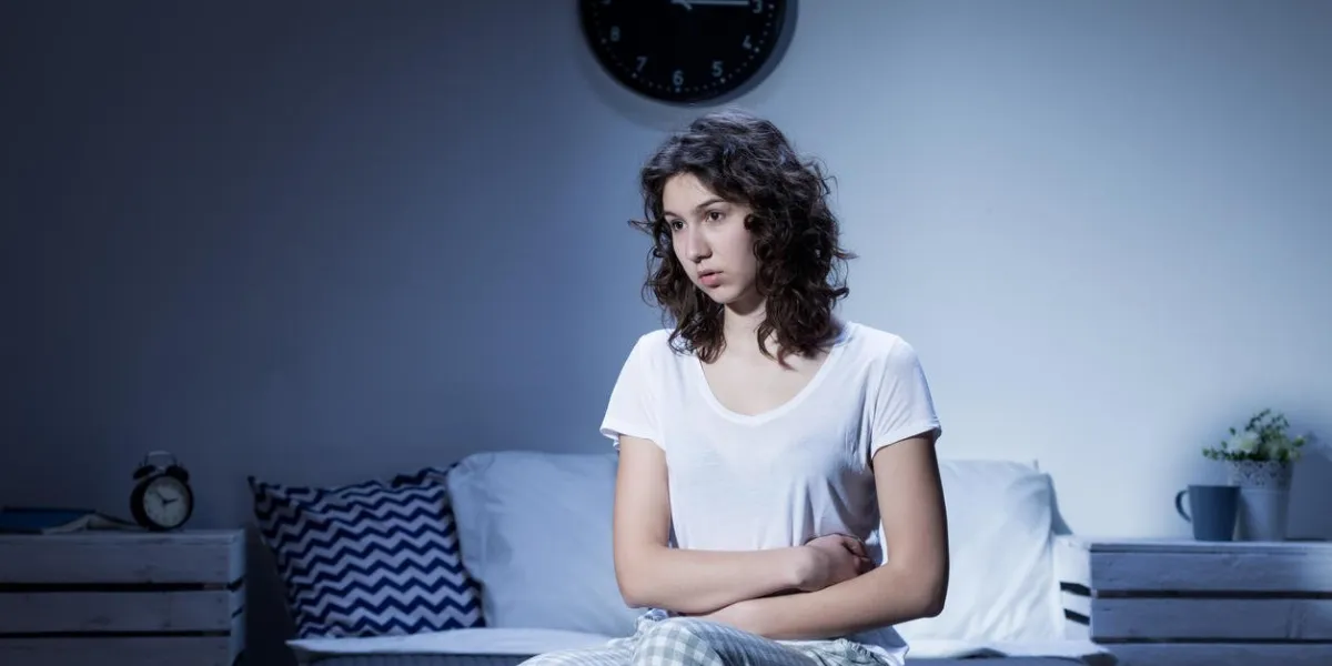 femme avec des douleurs à l'estomac assis sur le lit la nuit