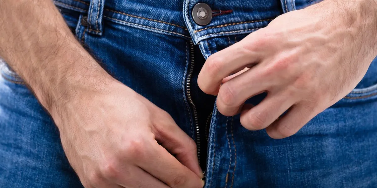 close-up of a man's hand unzipping the blue jeans