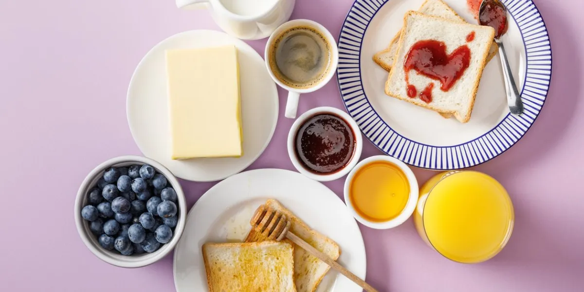 top view of served breakfast with cup of coffee and orange juice on violet background