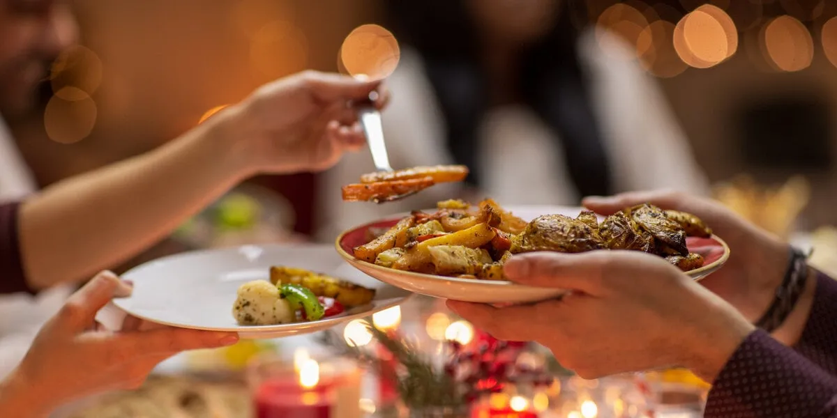 holidays, eating and celebration concept - close up of friends having christmas dinner at home and sharing food
