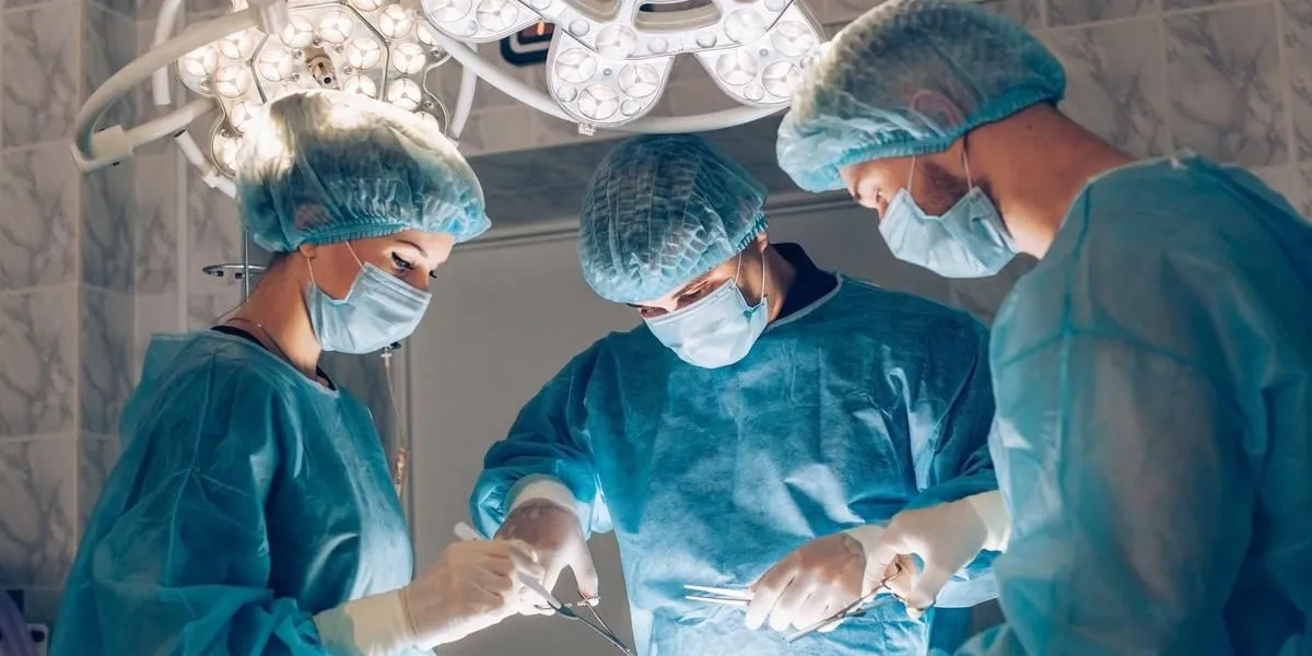 surgeons team working with monitoring of patient in surgical operating room breast augmentation