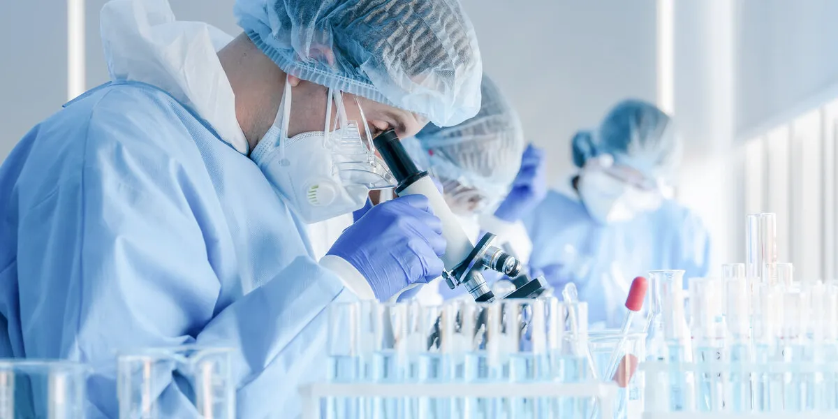 biochemical research scientist team working with microscope for coronavirus vaccine development in pharmaceutical research labolatory