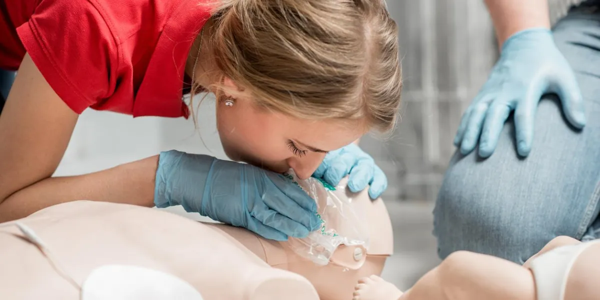 woman instructor showing how to make artificial respiration with dummy during the first aid training indoors