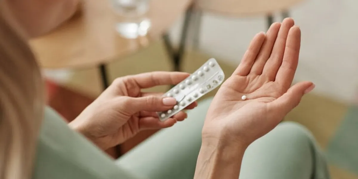 close up of unrecognizable woman taking birth control pill at home in open hand copy space