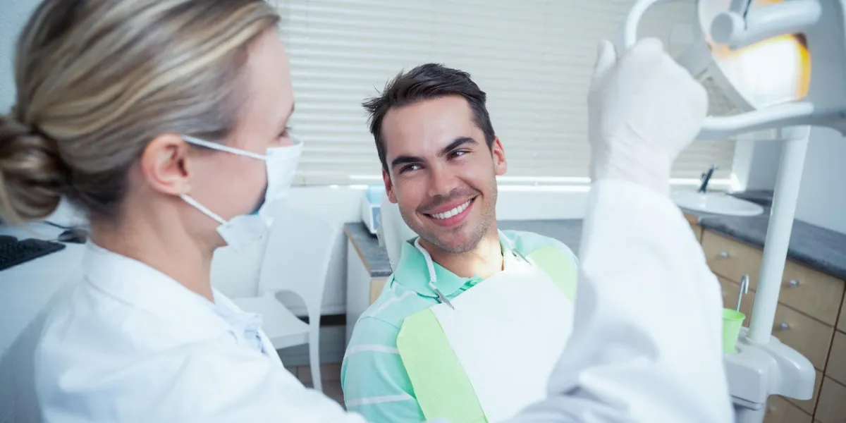 female dentist examining mans teeth in the dentists chair