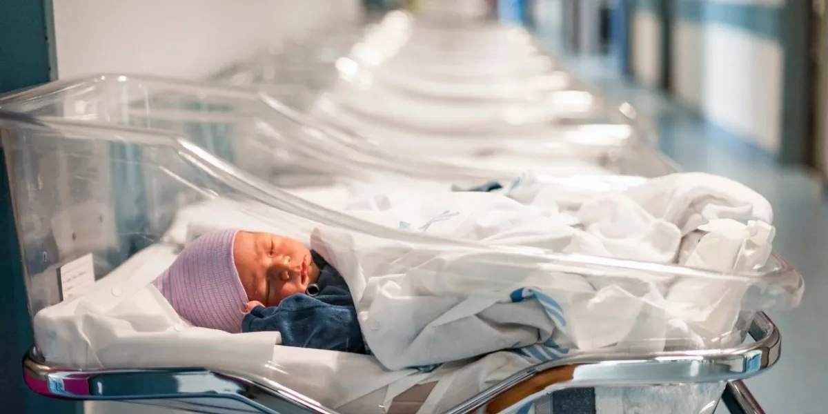 newborn baby boy in his small transparent portable hospital bed