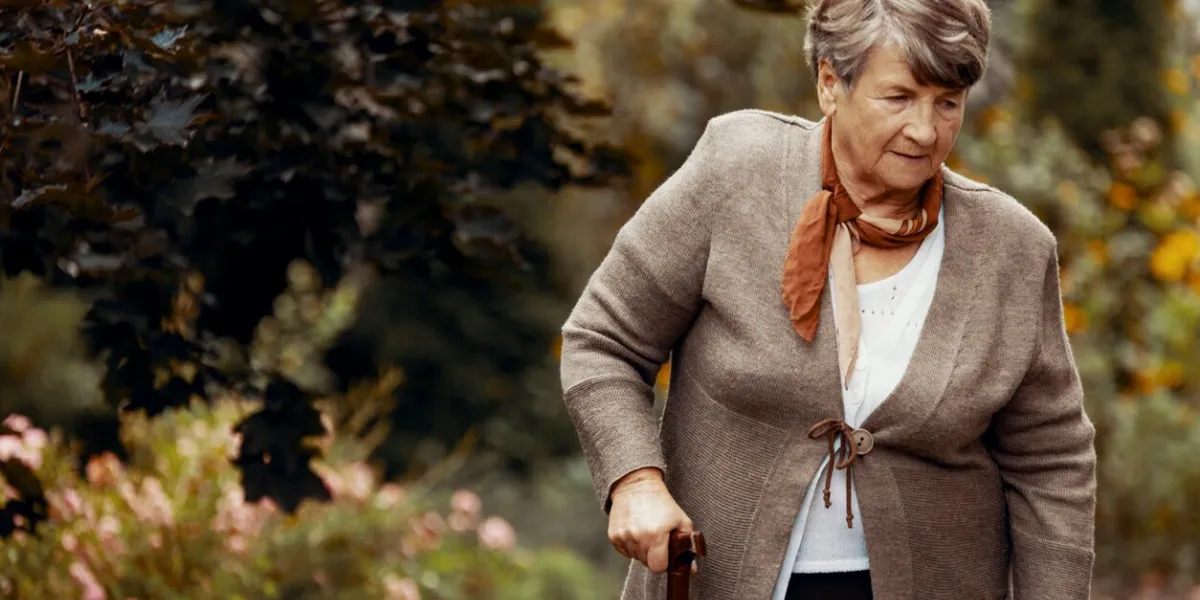 senior woman with walking stick on the walk in the park