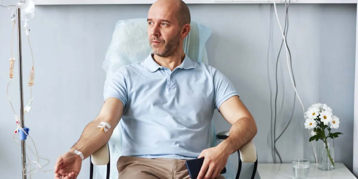portrait of adult man sitting in comfortable chair with iv drip during treatment session in clinic