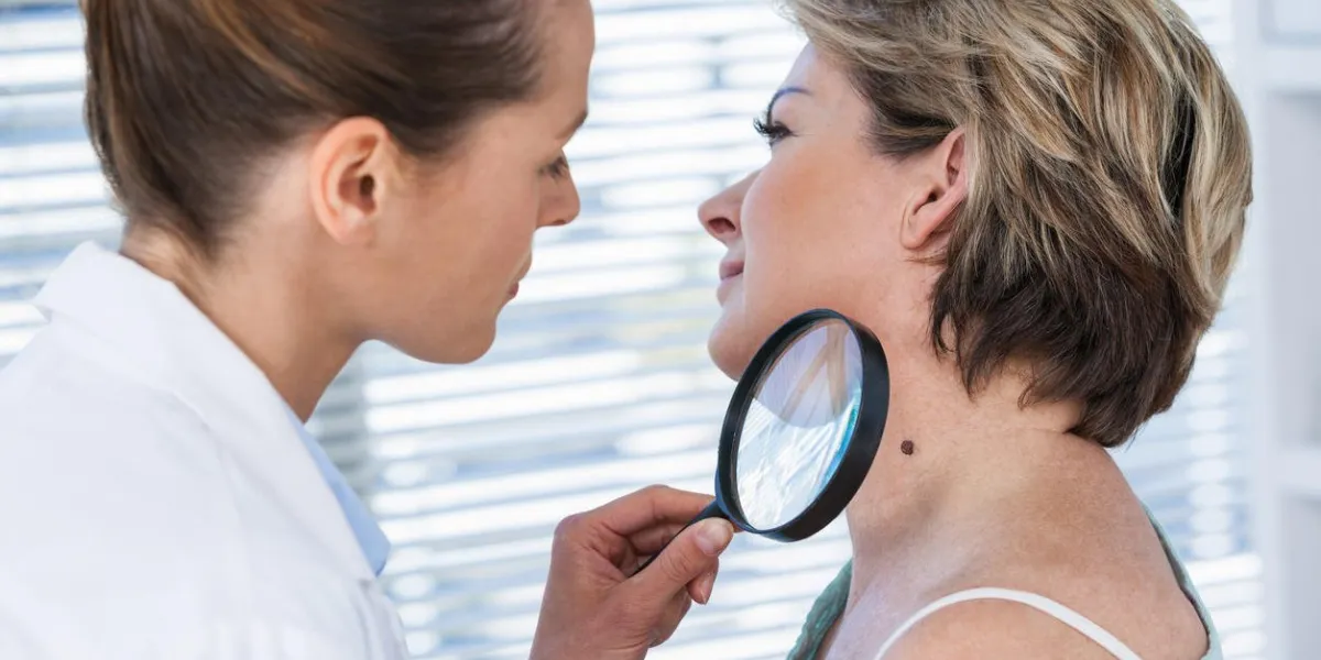 dermatologue examinant la taupe avec la loupe dans la clinique