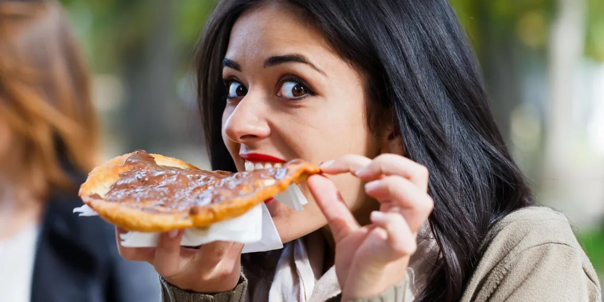 jolie fille affamée grignotant un scone au chocolat