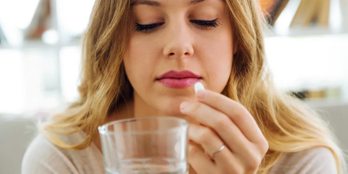 portrait of depressed young woman taking pills at home