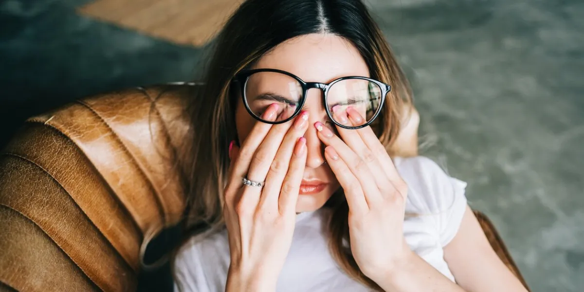 young woman rubs her eyes after using glasses eye pain or fatigue concept