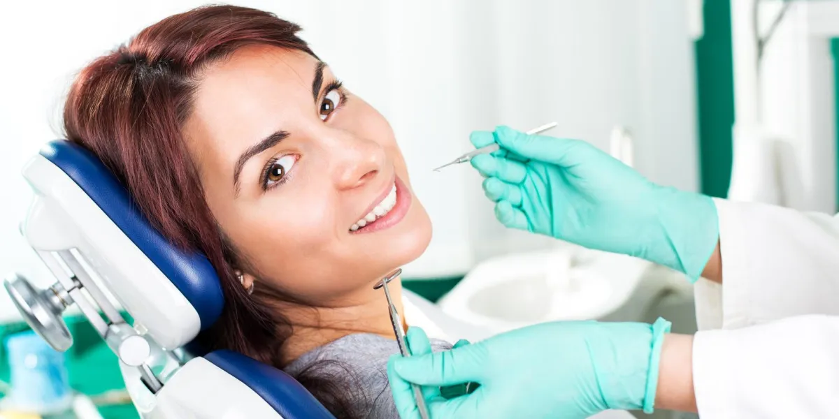 femme souriante au dentiste assis dans une chaise de dentiste prêt pour un examen dentaire
