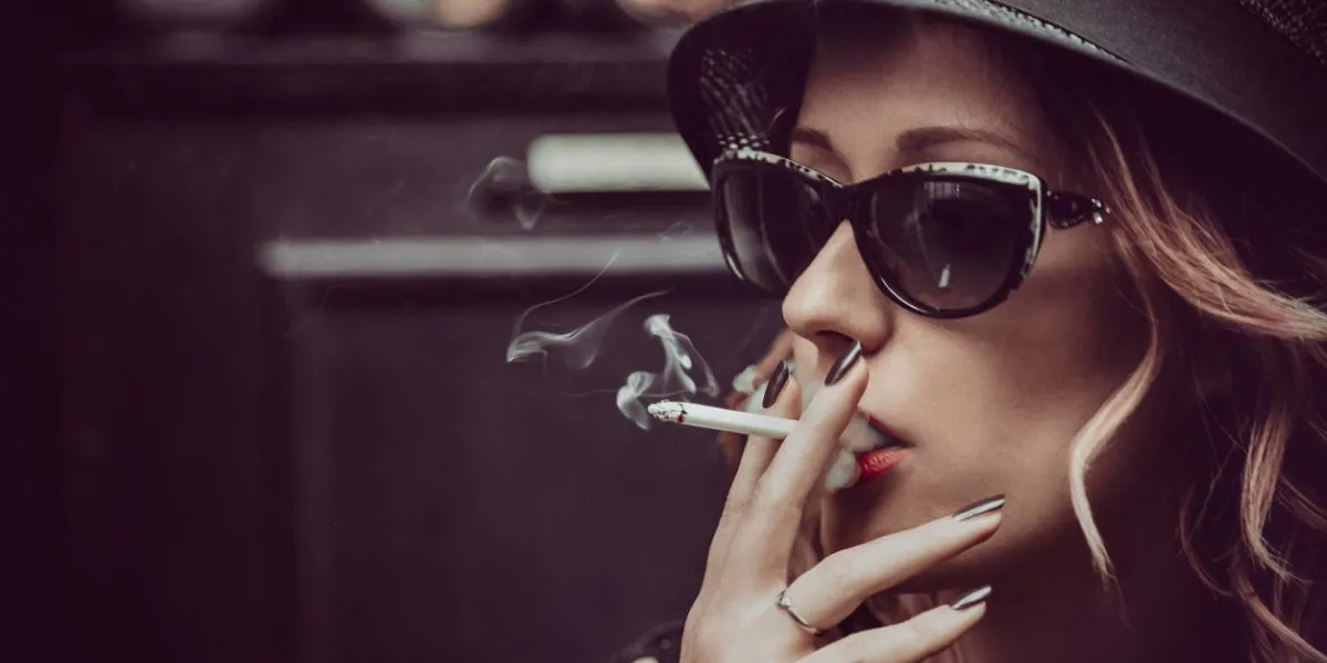 belle femme brune avec des lunettes de soleil, des lèvres rouges, fumer une cigarette