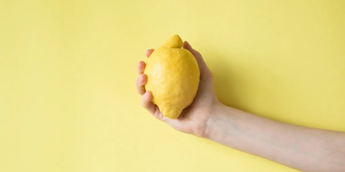 lemon in woman's hand on a yellow background