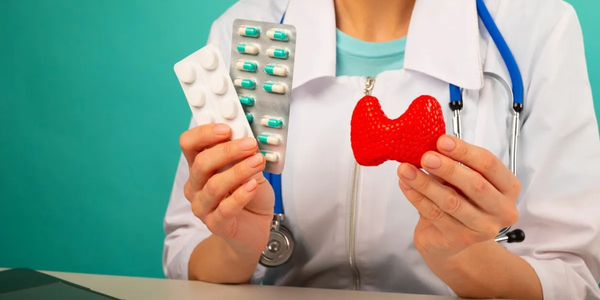 doctor holds model of thyroid gland and pills close-up protection, treatment, prevention concept