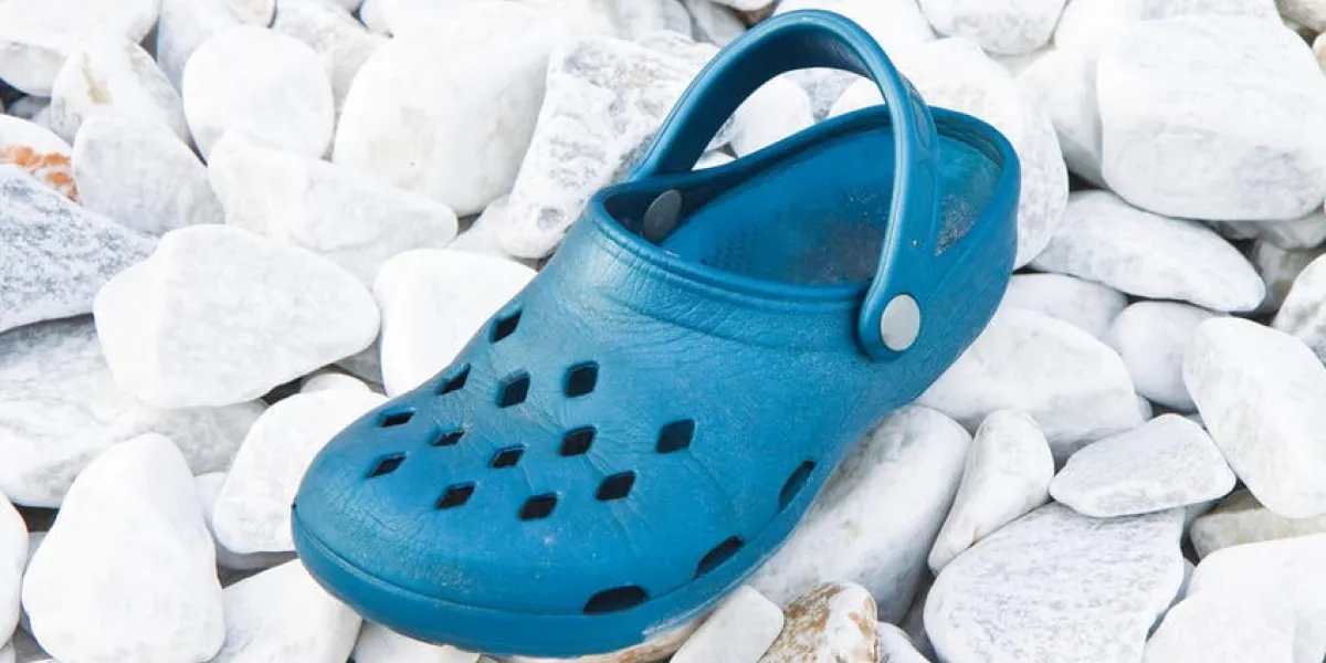 vieille pantoufle bleue abandonnée sur un rivage de galets de pierre