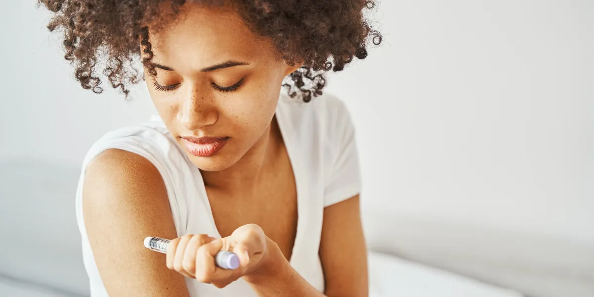portrait of a focused serious calm curly-haired attractive african american woman giving herself an injection