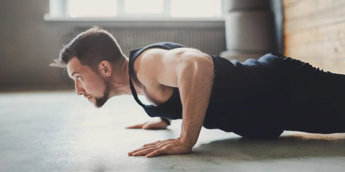 young man workout in fitness club profile portrait of caucasian guy making plank or push ups exercise, training indoors