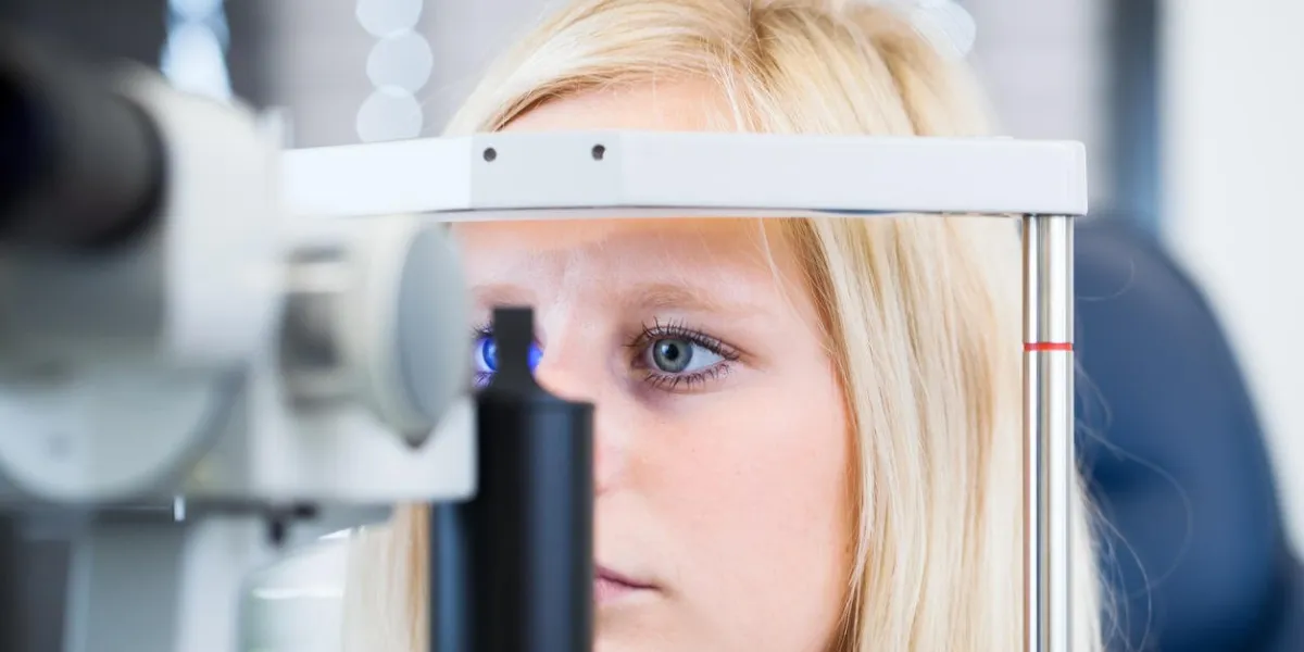 concept d'optométrie - jolie jeune femme ayant les yeux examinés par un ophtalmologiste (dof peu profond, image aux tons colorés)