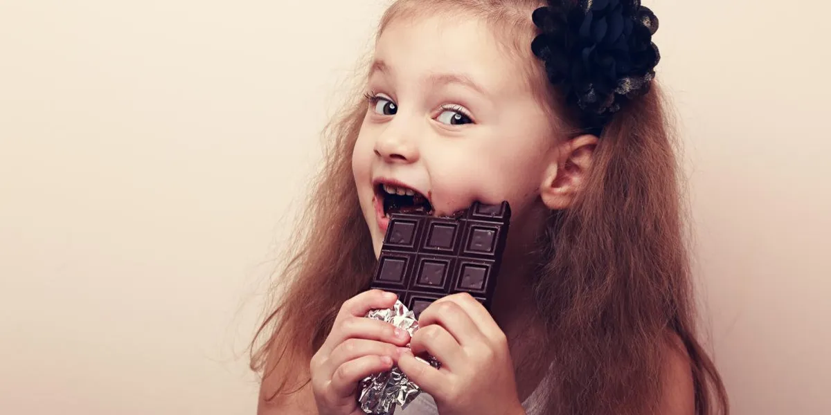 happy smiling kid girl biting tasty chocolate with empty copy space vintage portrait