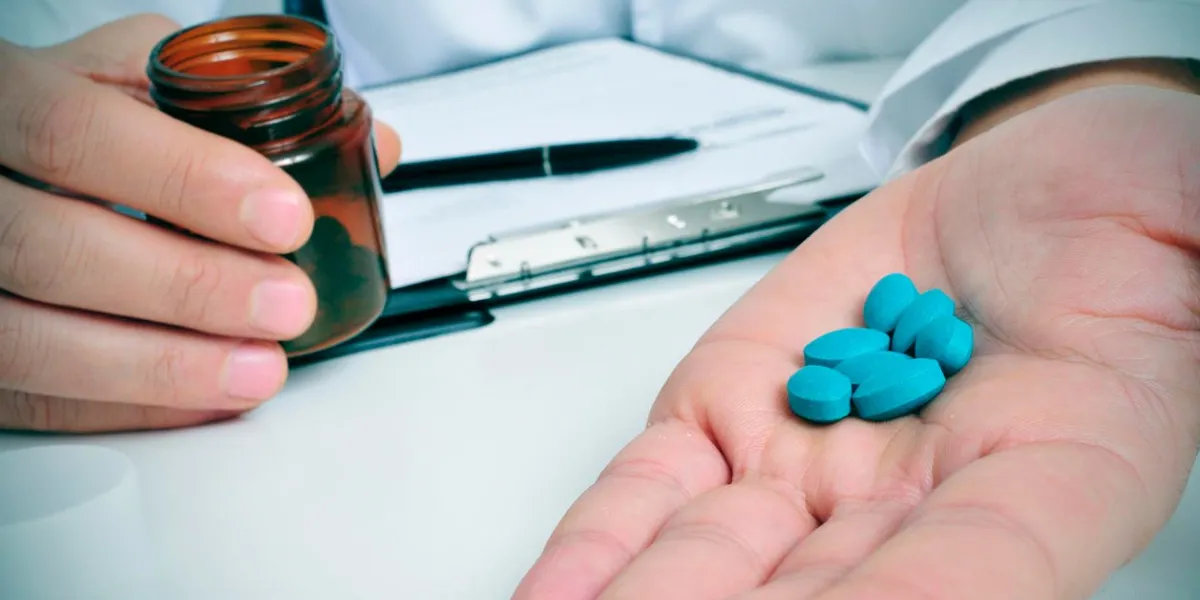 a doctor sitting in a desk with a pile of blue pills in his hand