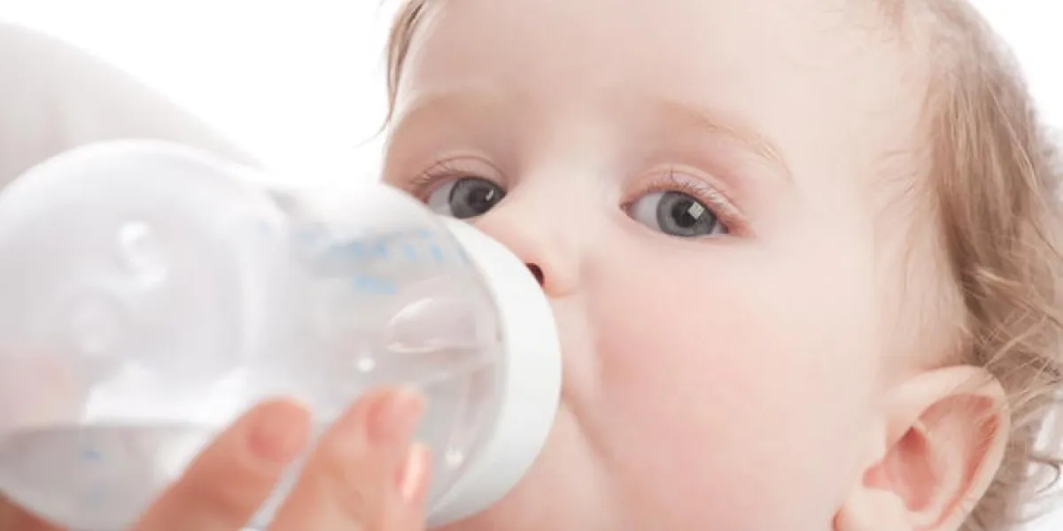 mère donne à boire son fils en biberon sur blanc
