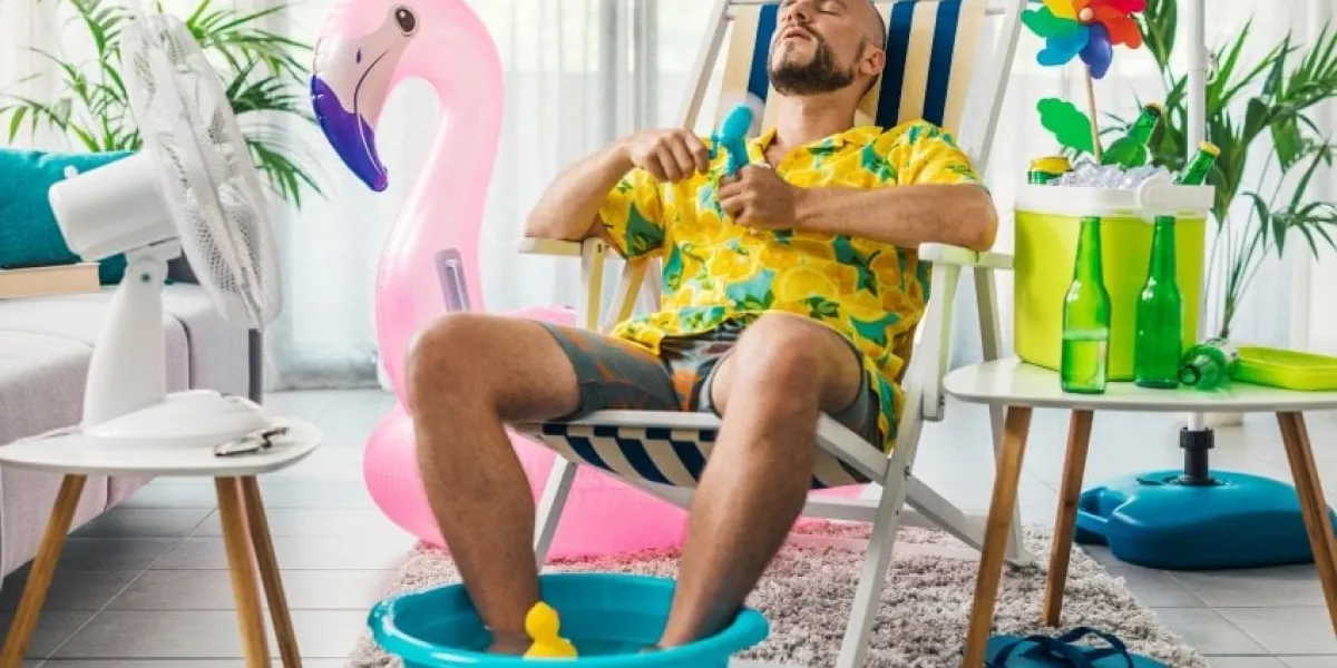 man spending summer vacations at home, he is cooling himself with electric fans and sitting on a deckchair