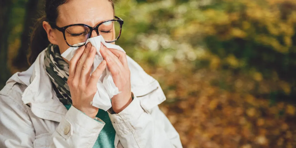 woman blowing her nose in the park