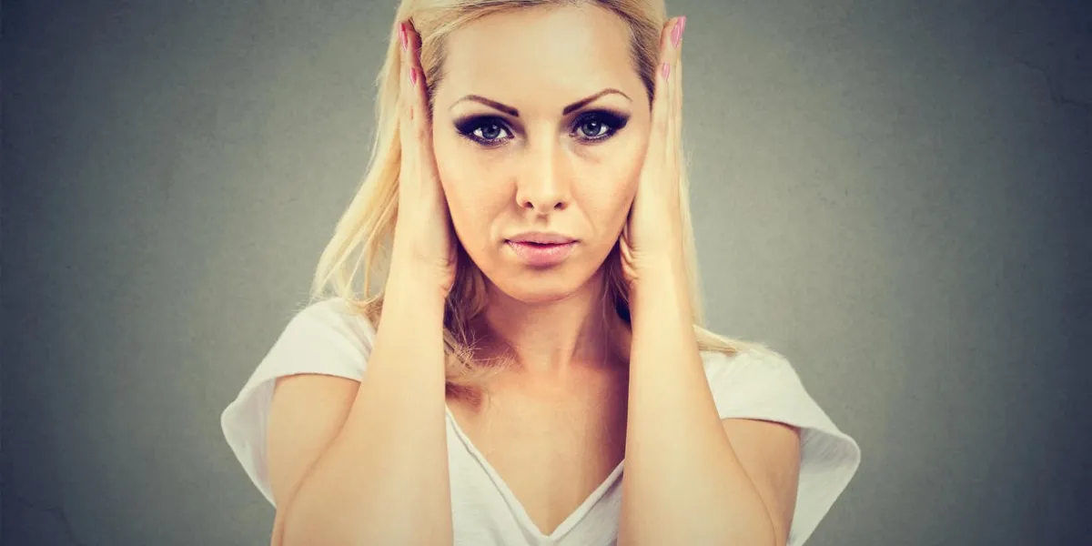 young serious woman covering ears from rumors and noise avoiding problems and looking annoyed