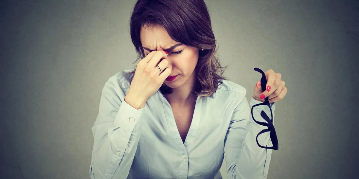 woman with glasses suffering from eyestrain after long hours working on computer