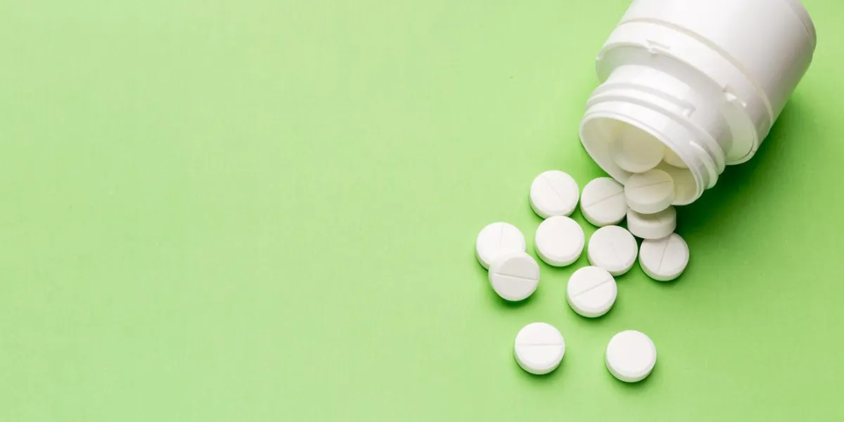 heap of round white tablets and plastic pills bottle