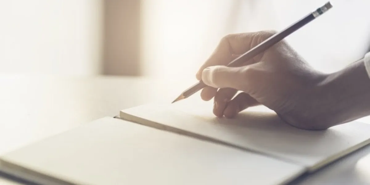 close up of male hand writing with pencil on the book businessman working with data information in the office