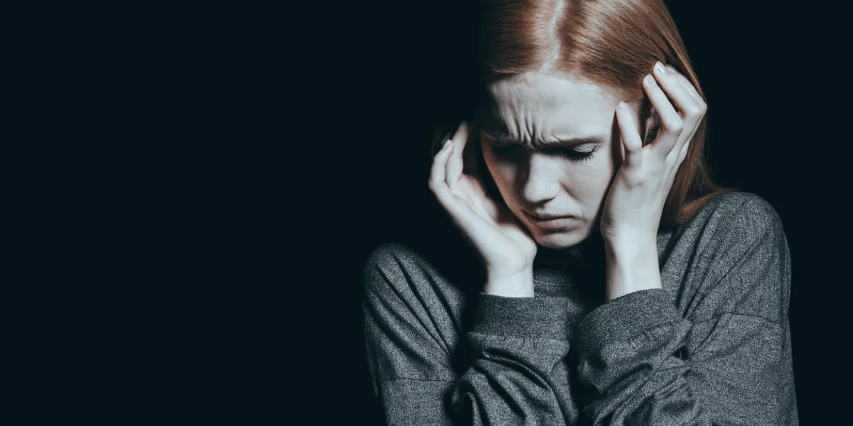 fearful woman covering her ears, vitctim of domestic violence