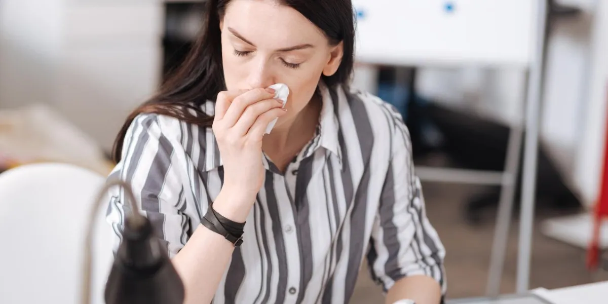 terrible rhinitis inactive office worker wearing striped shirt keeping her eyes closed while turning head aside
