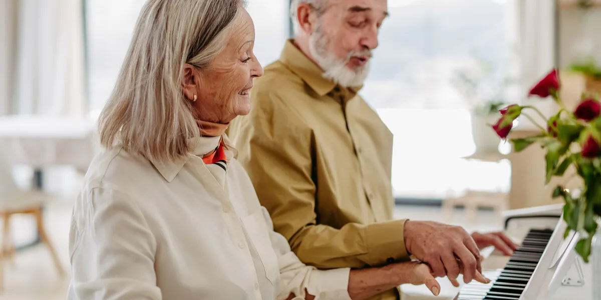senior couple playing on piano together in their livingroom