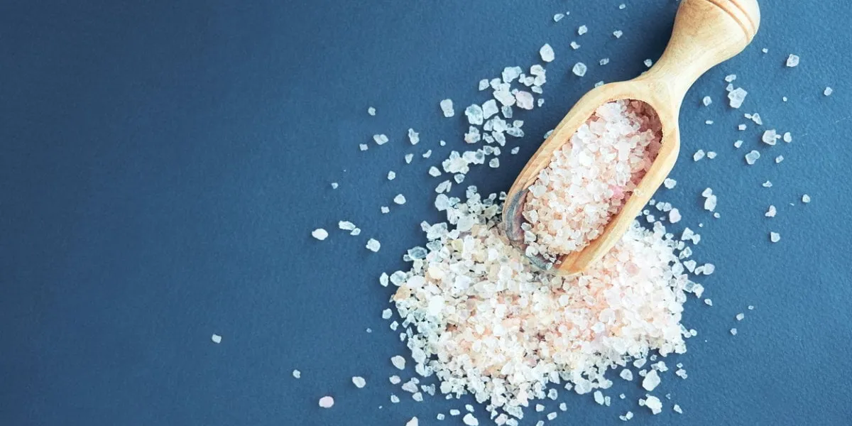 bowl of pink himalayan salt on dark table, top view, copy space