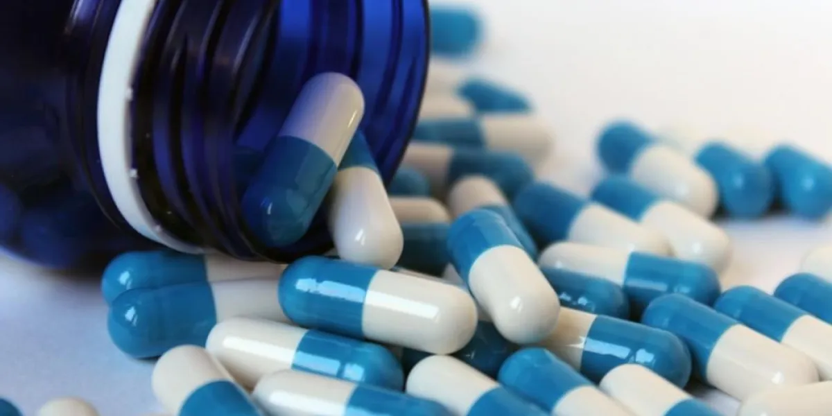 blue and blue tablets in a jar and around a jar of medicine