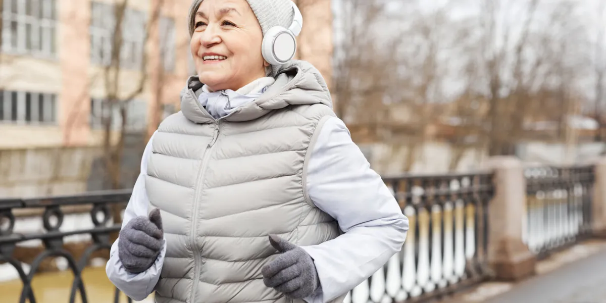 waist up portrait of active senior woman running outdoors in winter and smiling happily, copy space