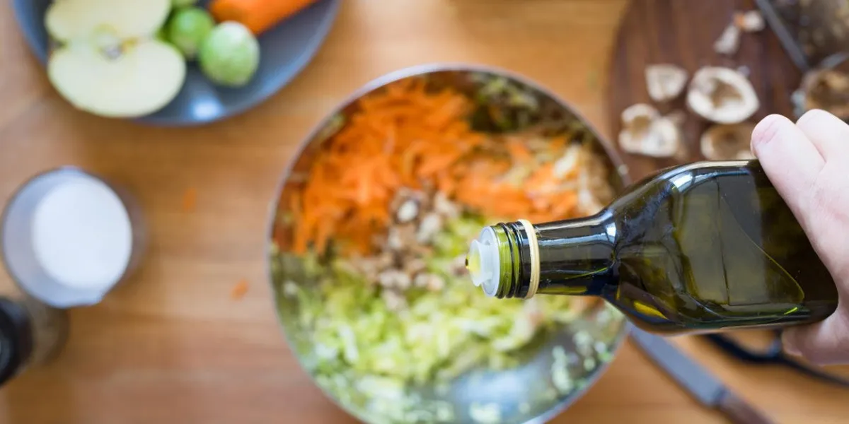 verser l'huile d'olive de la bouteille sur la salade de chou et de carotte