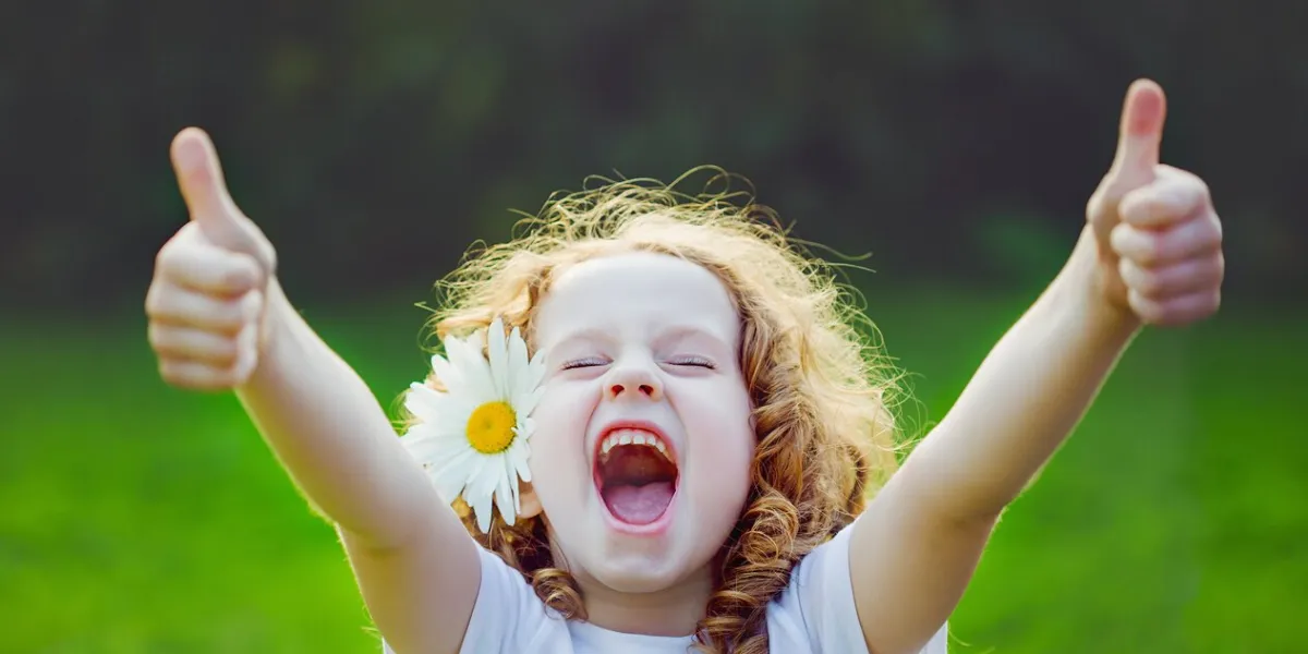 laughing girl with daisy in her hairs, showing thumbs up