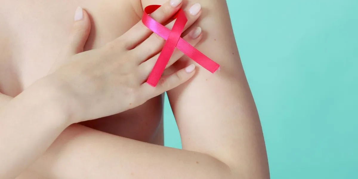 concept de sensibilisation de soins de santé, de médecine et de cancer du sein jeune femme nue avec le symbole de ruban rose couvrant sa poitrine, sur bleu