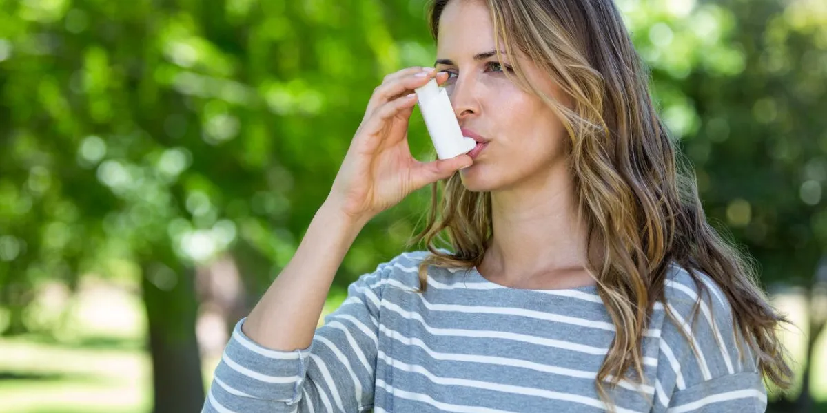 woman using asthma inhaler in a park