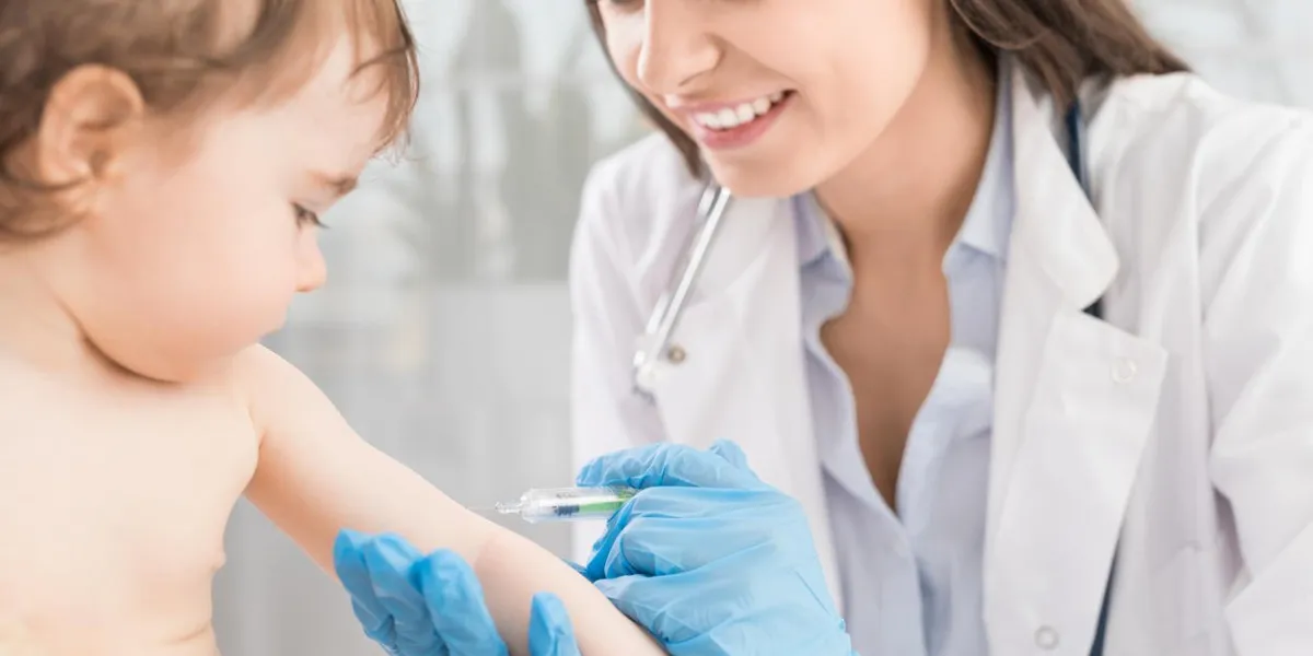 young woman pediatrician performs a vaccination of a little girl the girl is holding a mascot