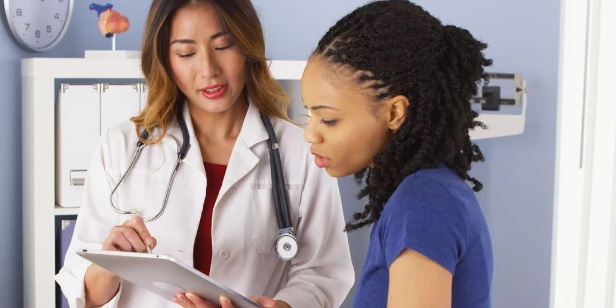 patient afro-américain expliquant des problèmes à un médecin asiatique à l'aide d'une tablette