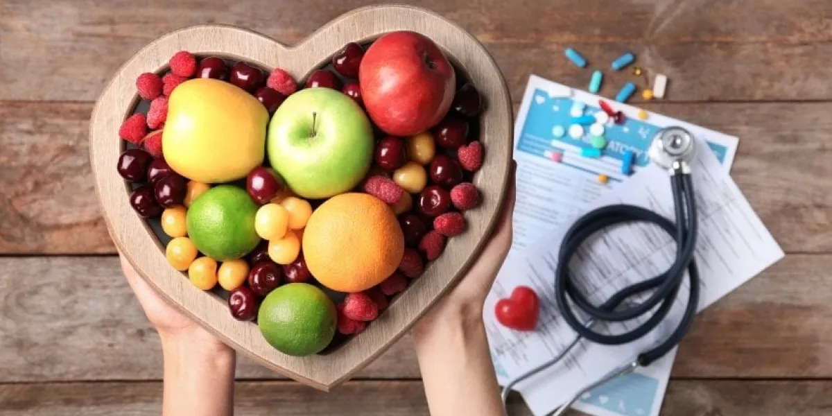 female doctor holding plate with fresh fruits over wooden table, top view cardiac diet